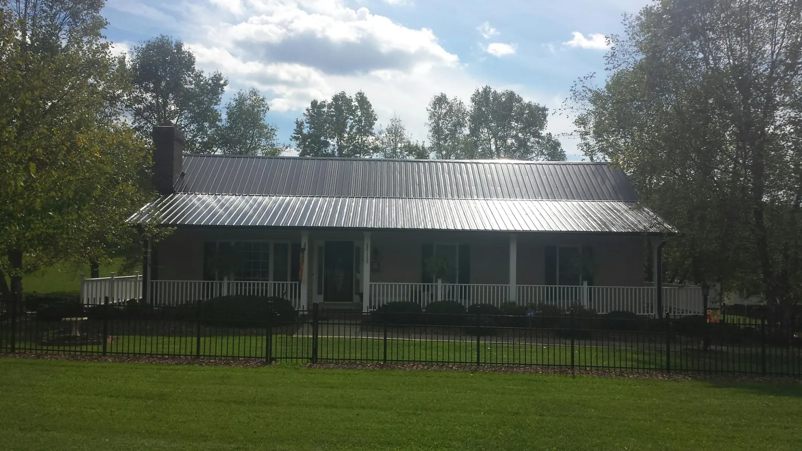 Gray metal roof on a brick ranch with a full width front porch — Gutter Guard Installation work by our crew in Unionville